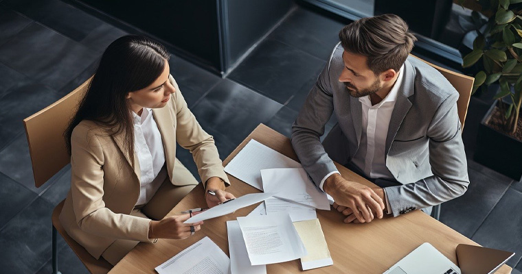 Man and woman reviewing printed brand guidelines and logo files at a table.
