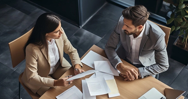 Un homme et une femme examinent à une table des directives de marque imprimées et des fichiers de logo.